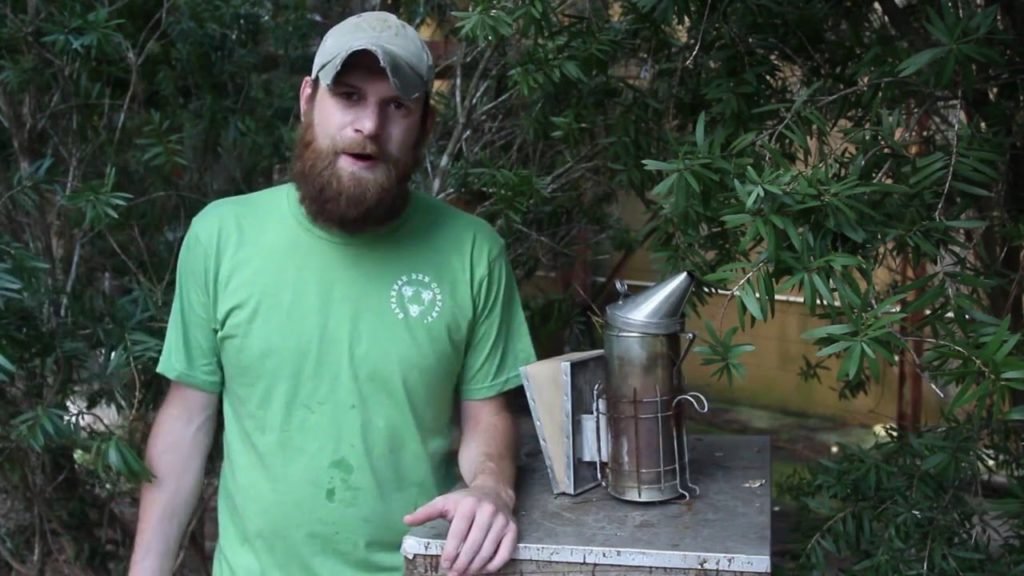 beekeeper demonstrating beehive smoker on homestead